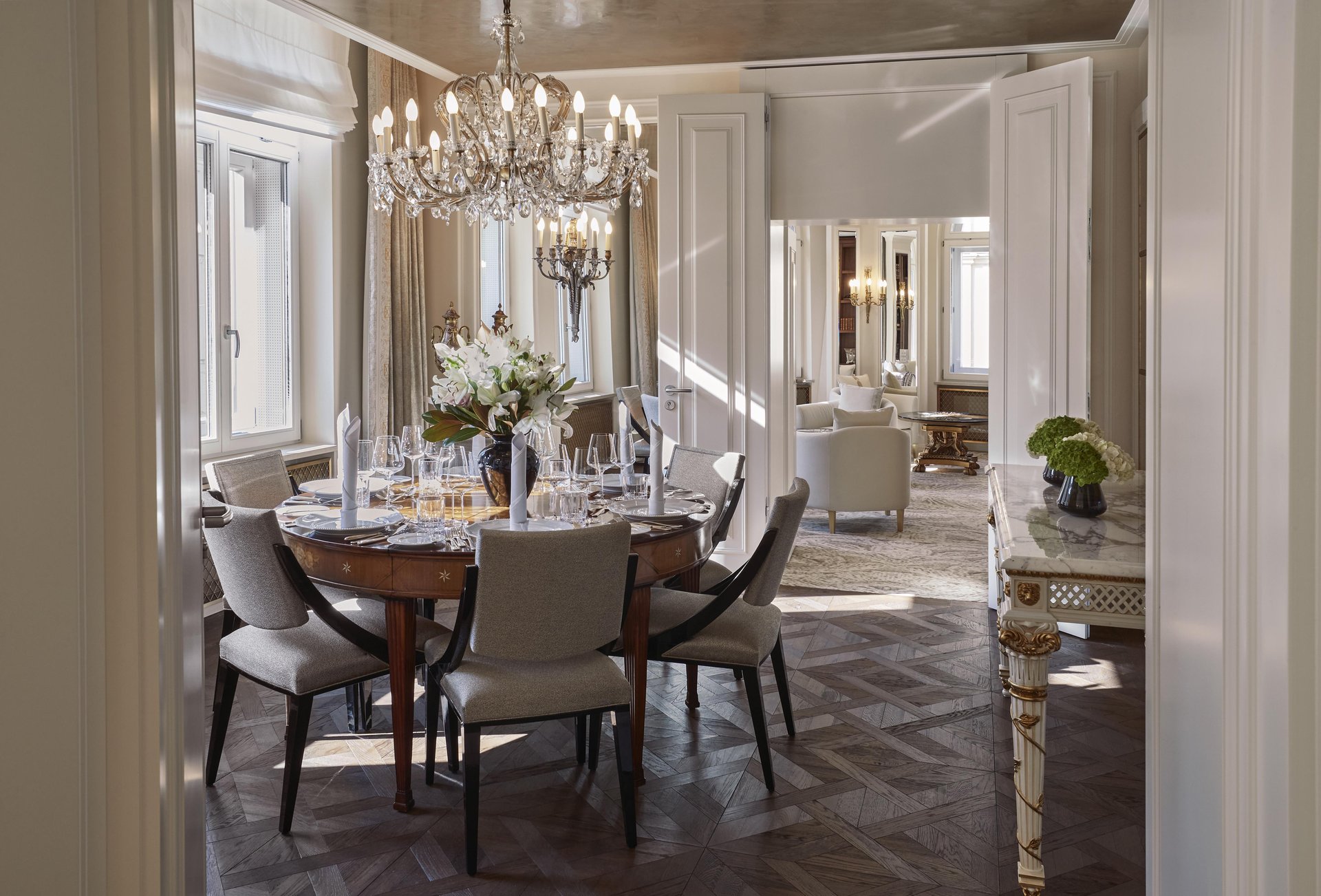Elegant Ludwig Suite dining room with crystal chandelier and parquet floors at Hotel Vier Jahreszeiten Kempinski München