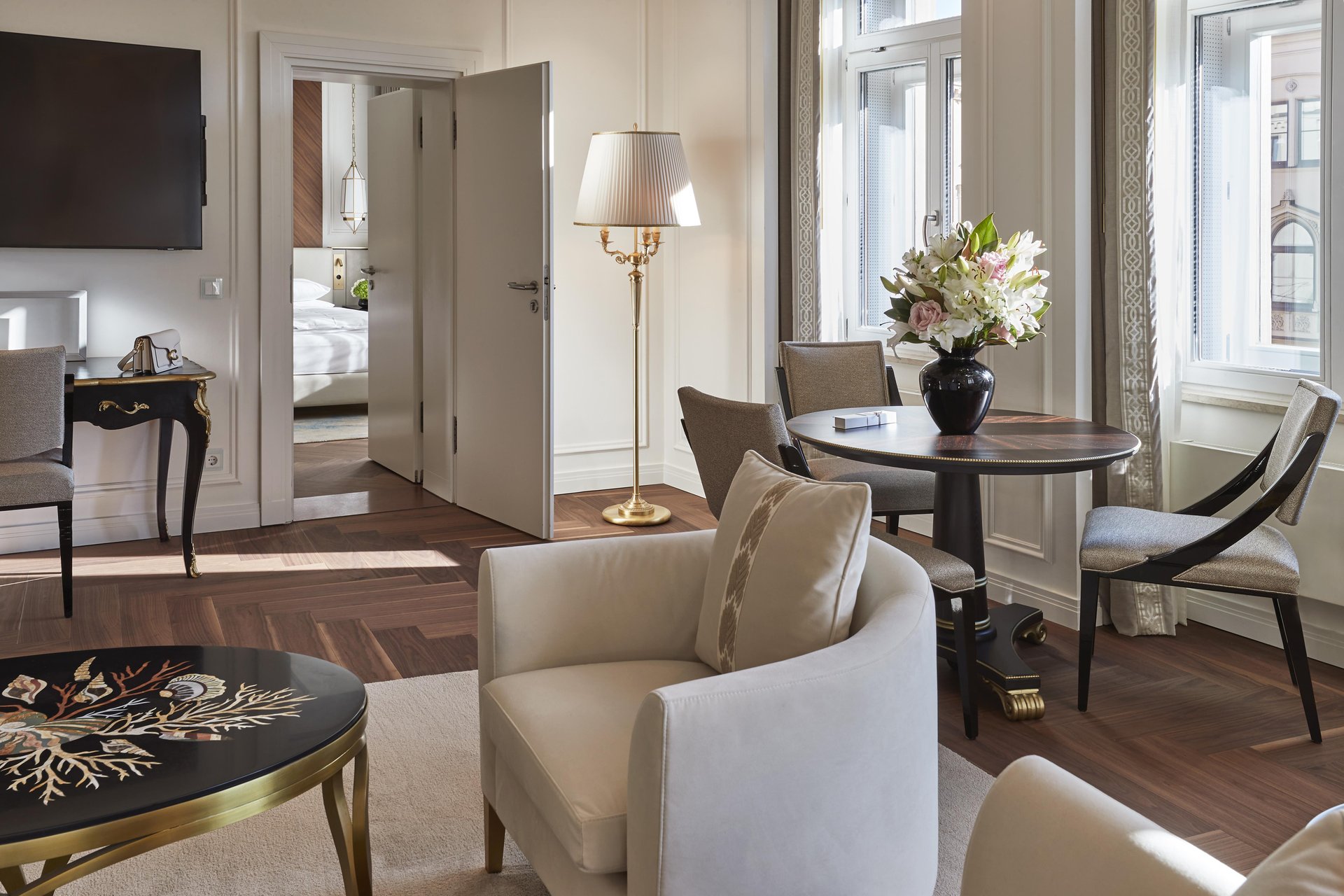 Elegant suite living area with parquet floors and round dining table at Hotel Vier Jahreszeiten Kempinski München