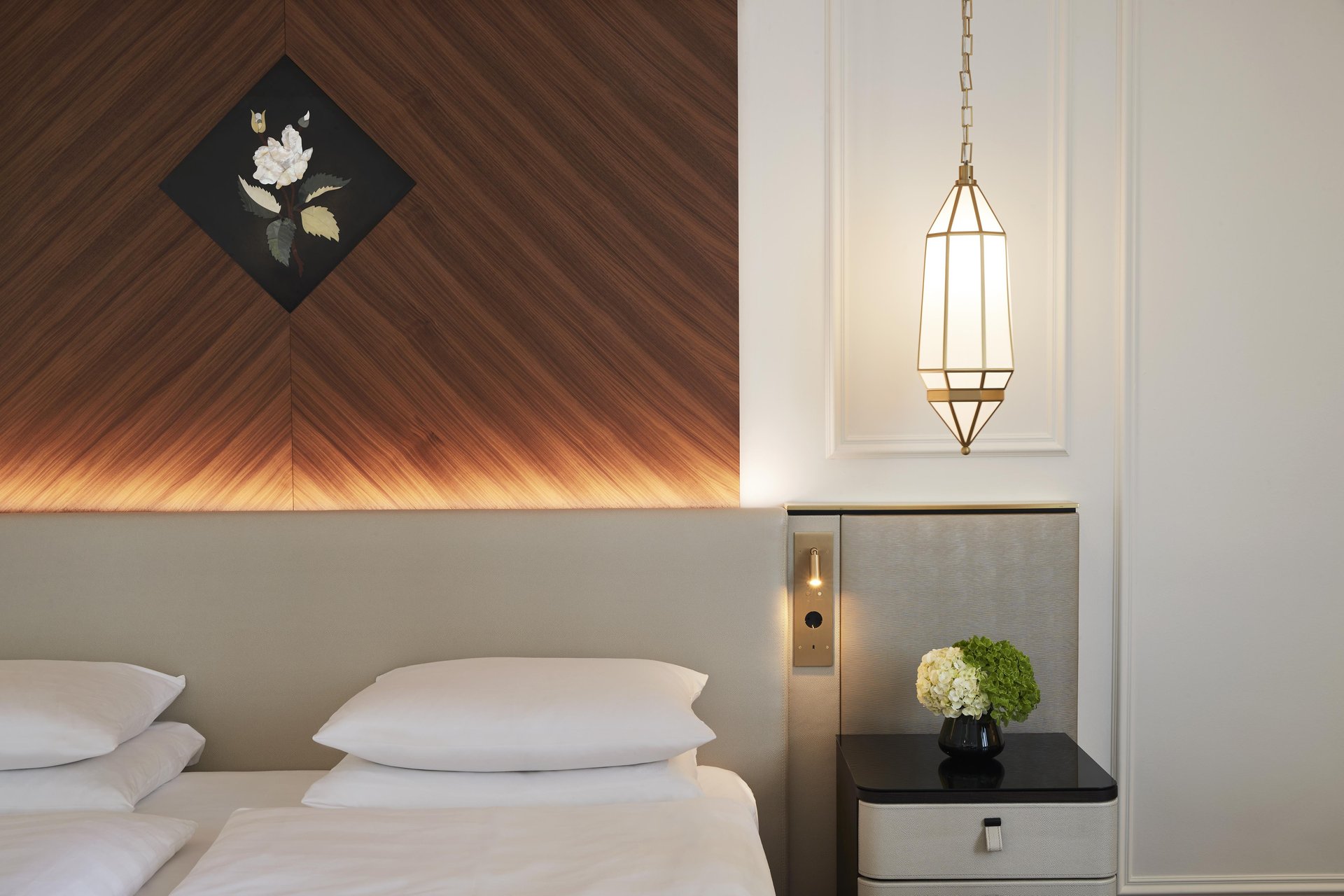 Luxury bed with wood-paneled headboard at Hotel Vier Jahreszeiten Kempinski München