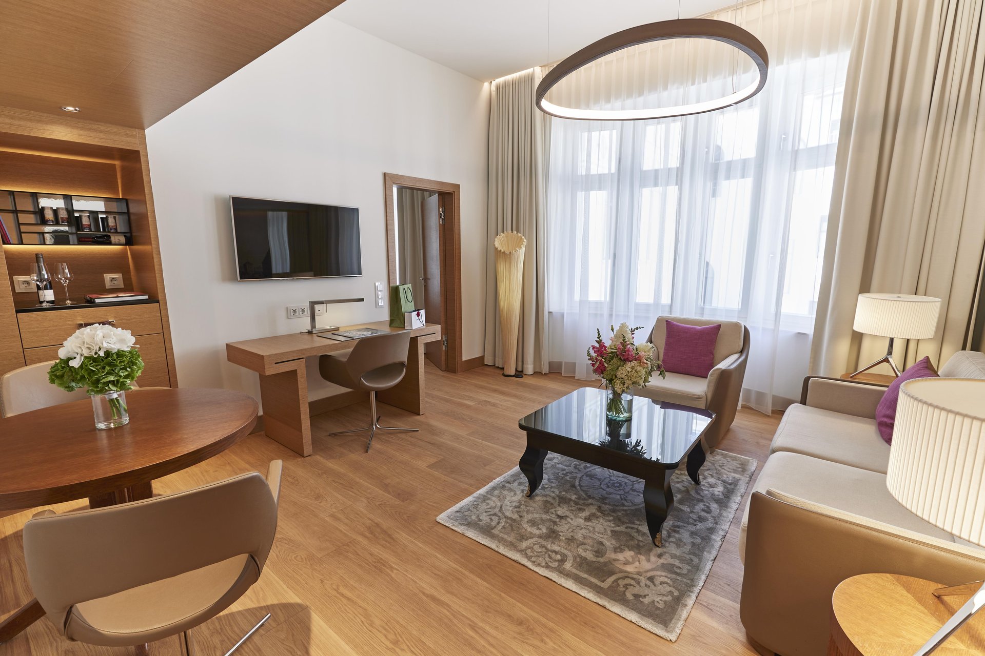 Suite living room featuring a dining table and work desk at Hotel Vier Jahreszeiten Kempinski München