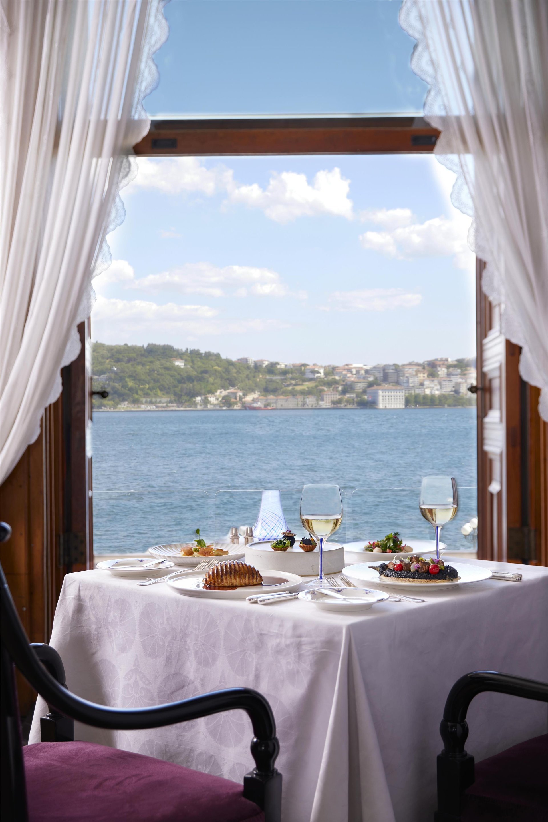 Romantic dinner setting at Tugra with candlelit table inside the Ottoman palace dining room overlooking the Bosphorus