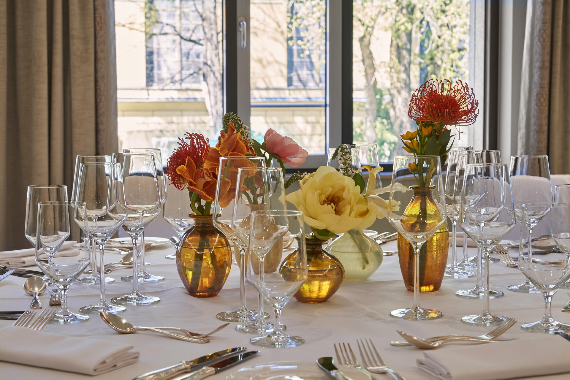 Close-up of banquet table with colorful flower vases and fine glassware at Hotel Vier Jahreszeiten Kempinski München