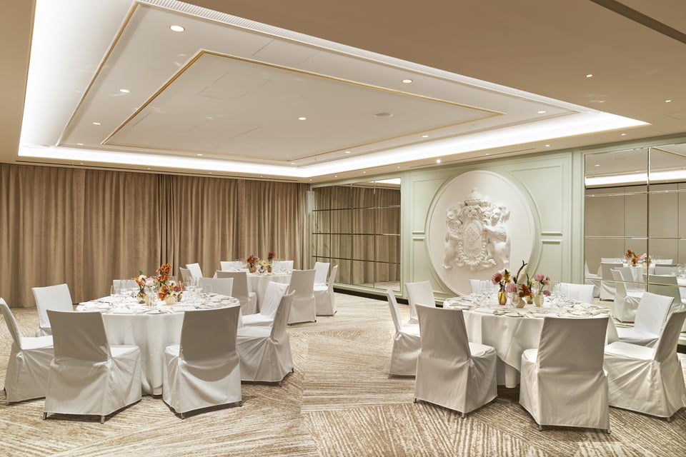Elegant banquet hall with round tables and white chair covers at Hotel Vier Jahreszeiten Kempinski München